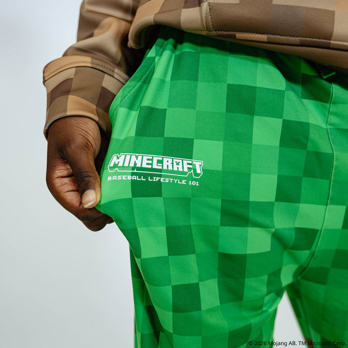 Youth model wearing green and brown youth pajama pants with "BL101 X Minecraft Grass Block" design
