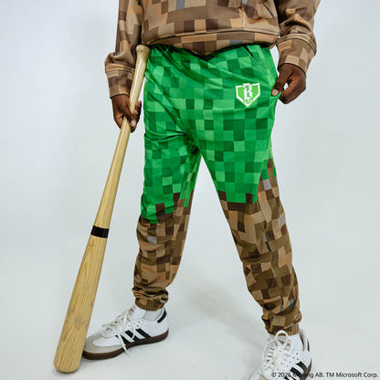 Youth model wearing green and brown youth pajama pants with "BL101 X Minecraft Grass Block" design